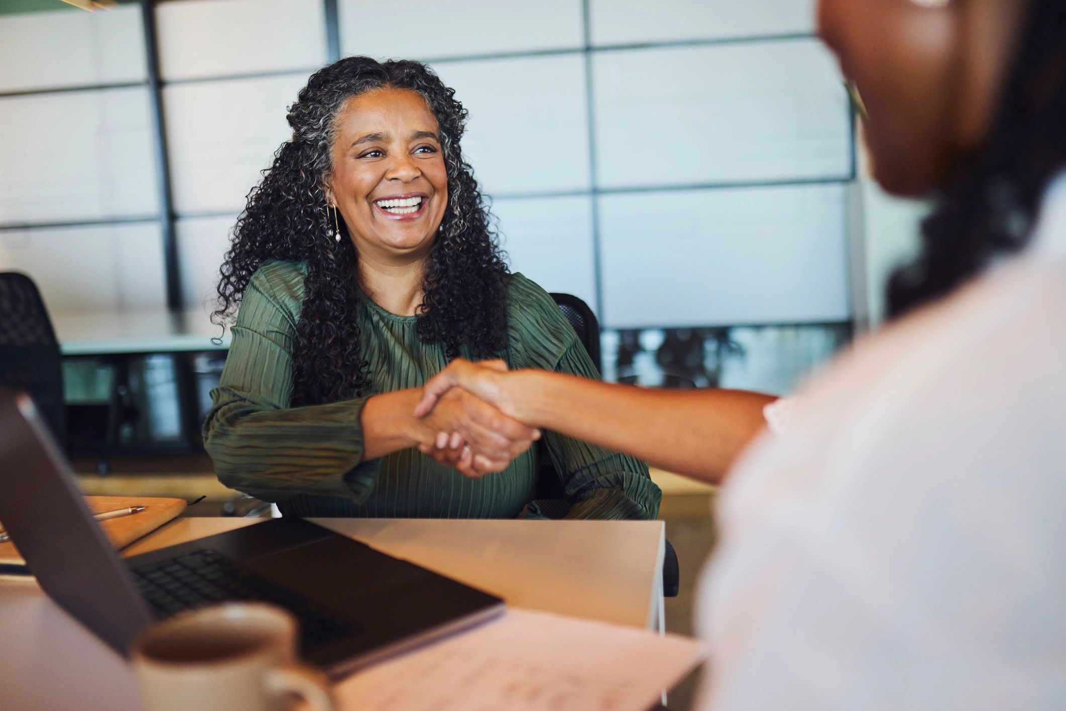 Business partners shaking hands across a meeting table
